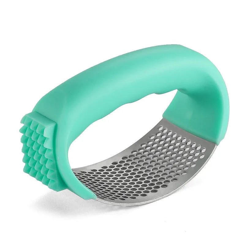 Stainless steel garlic press in green colour with ergonomic handle, measuring 11cm by 7cm on a kitchen counter