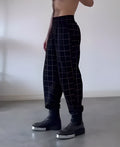 Men's plaid trousers featuring an apron-style front pocket panel in a tartan pattern.