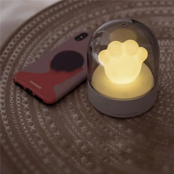 Grey cat paw shaped night light with USB charging port and control button showing soft illumination