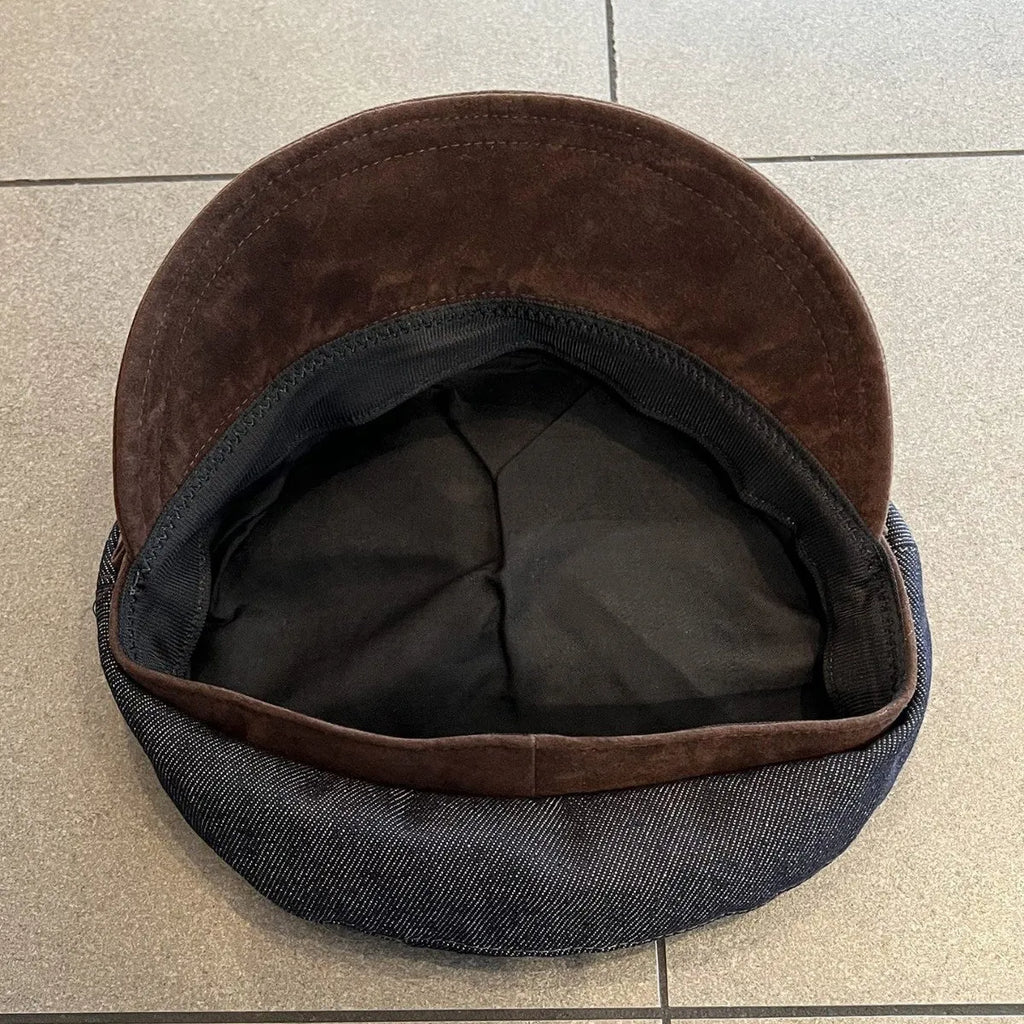 Dark blue denim British retro octagonal newsboy cap with an adjustable strap and coloured brim option on display.