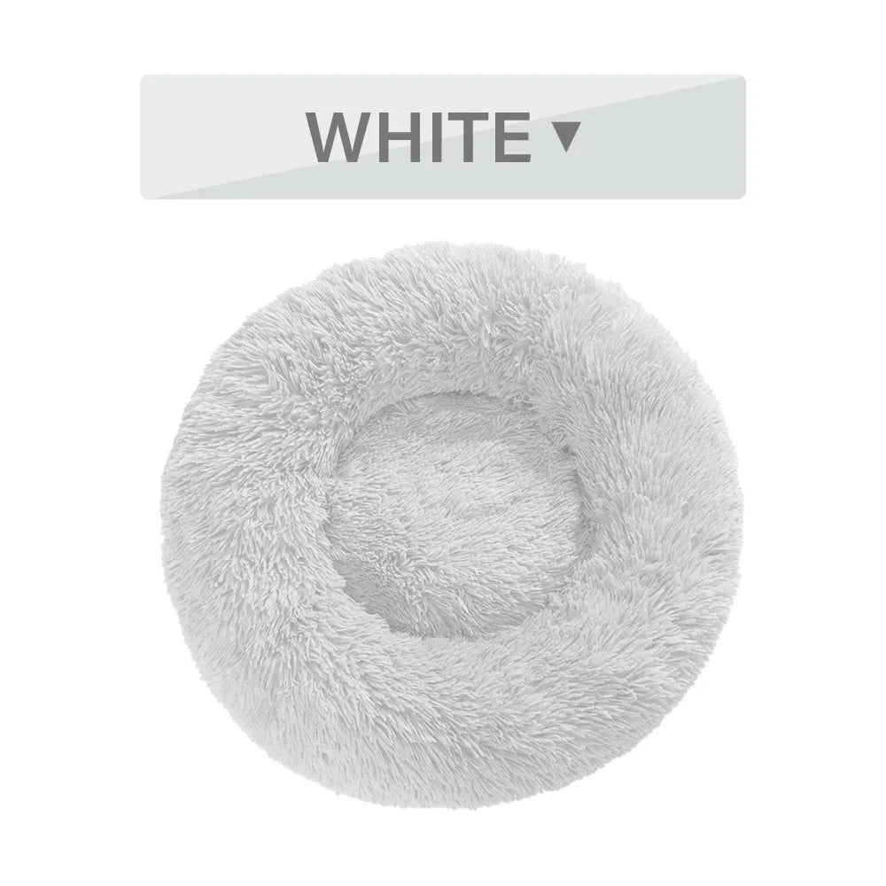 Fluffy donut-shaped dog bed in long plush fabric, shown in a light grey colour with a raised bolster edge.