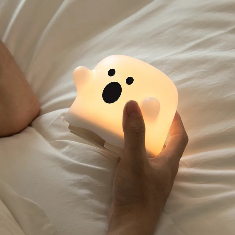 White silicone touch sensor LED night light on a bedside table.