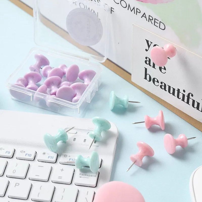 Box of plastic push pins in mint green, pink, and lavender colours, showing large and small thumbtacks for bulletin boards.