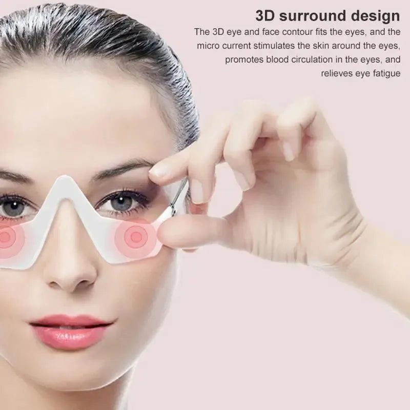 Pink and white USB rechargeable micro-current eye massager with glasses-style frame on a grey background.
