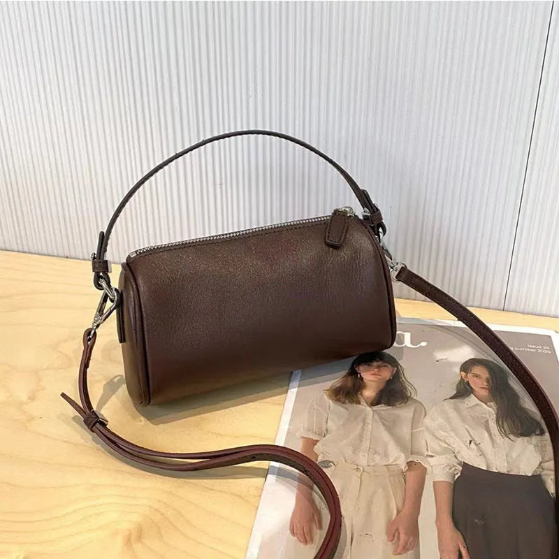 Cylindrical leather crossbody bag for mobile phones in six colours, showing visible sewing thread and compact size.