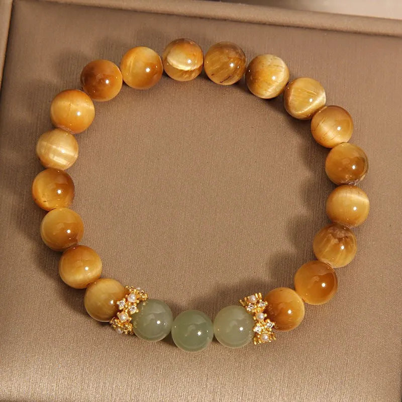 Natural yellow tiger's eye stone bead bracelet with gold gourd charm on a white background.