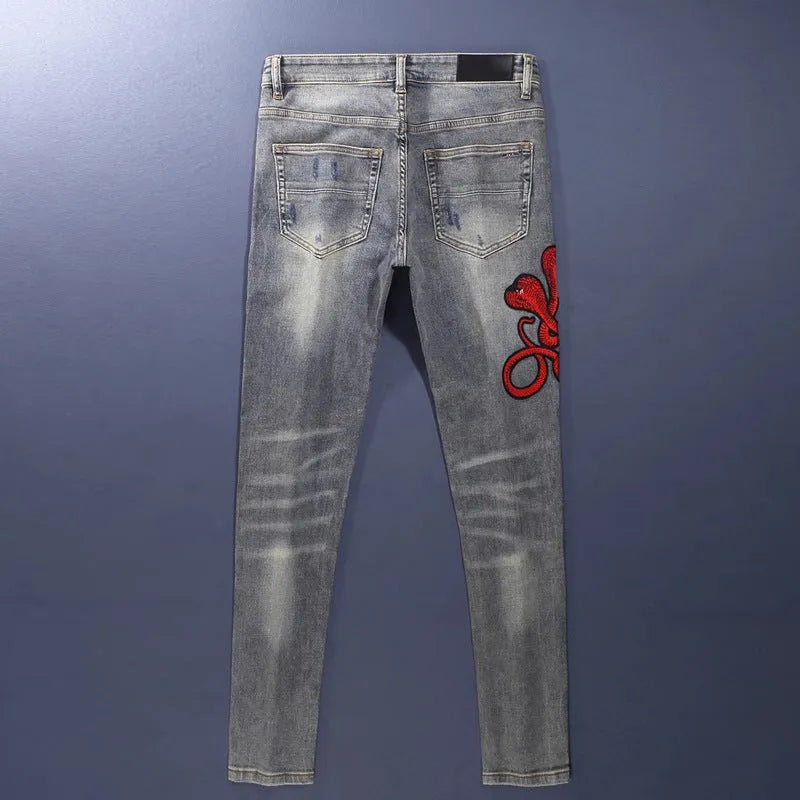 Men's slim fit distressed jeans with embroidered patches in an old colour wash.