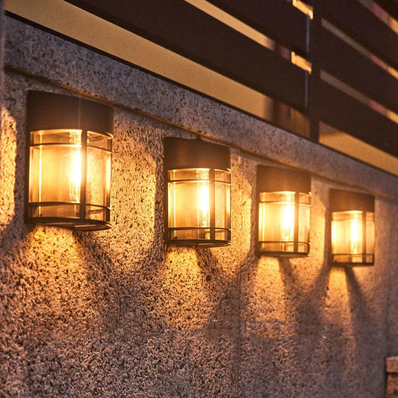Tungsten-style solar-powered outdoor wall light with automatic light sensor mounted on a garden wall.