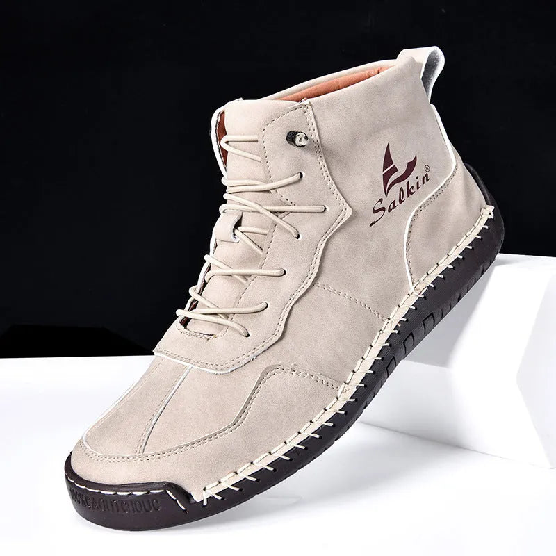 A pair of beige retro high-top casual leather boots with a round toe and elastic band fastening on a plain background.