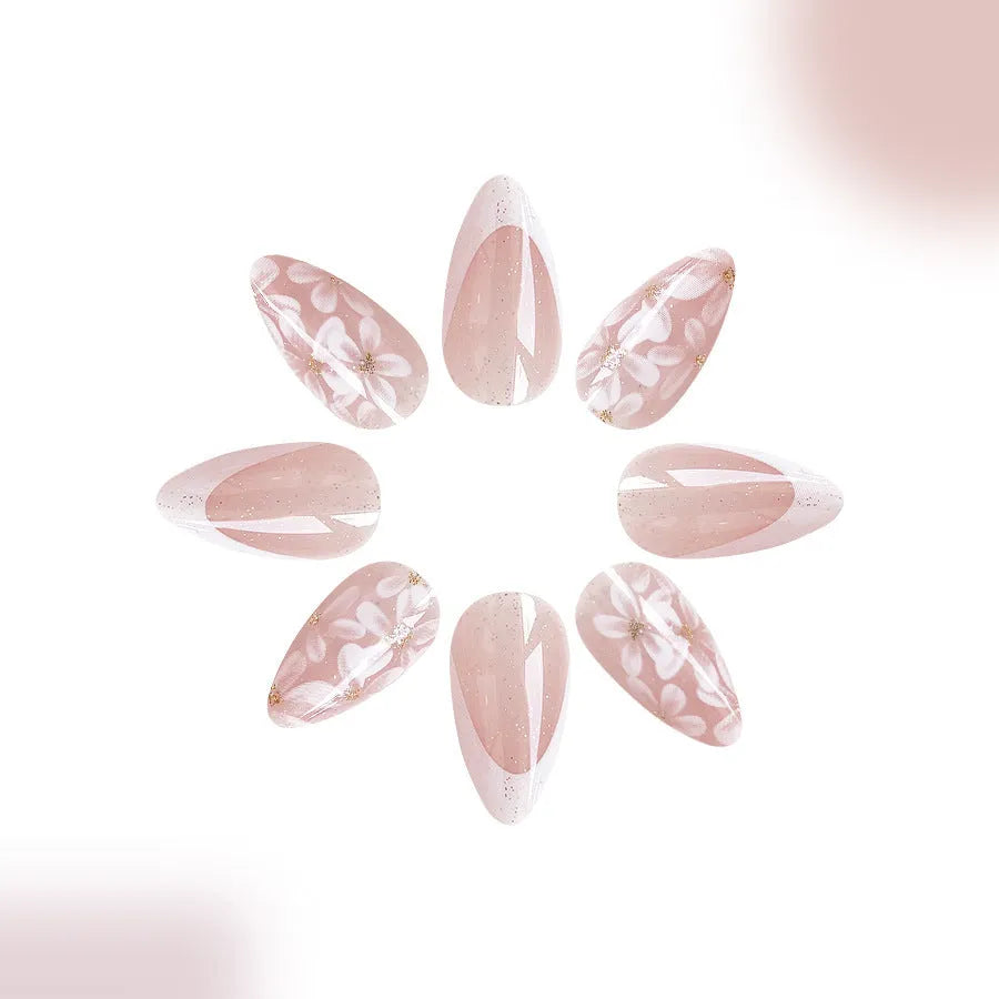 Short almond-shaped artificial nails with white French tips and glittering powder flower designs on translucent base