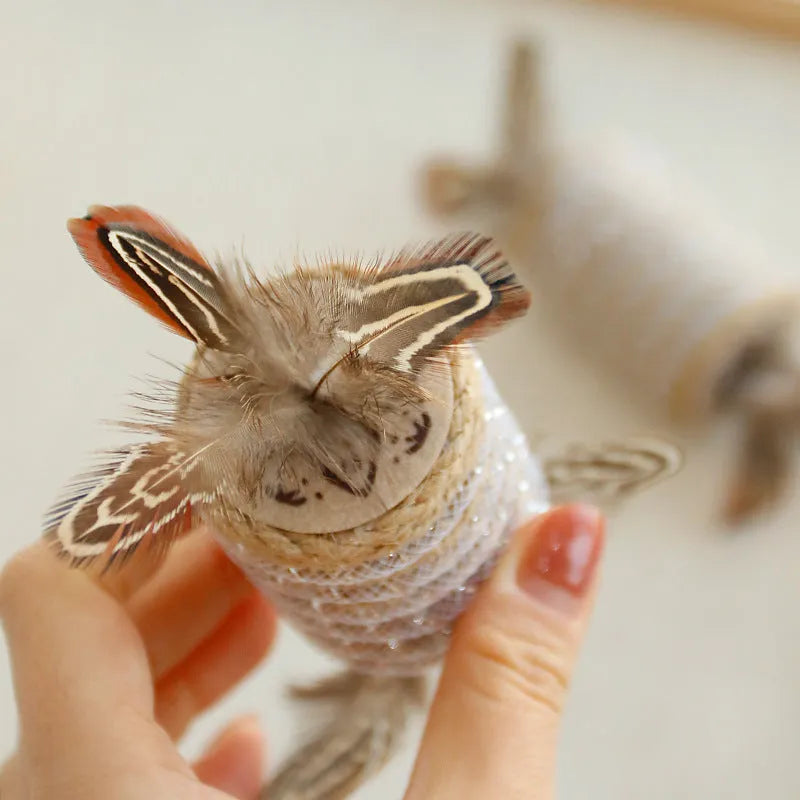 Beige cat interactive toy with feathers, hemp rope scratching surface, and integrated sound roller mechanism