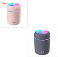 Pink USB mini humidifier with colourful lights on wooden desk