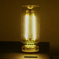 Small transparent glass USB touch night lamp with platinum base on a surface, showing warm white glow.