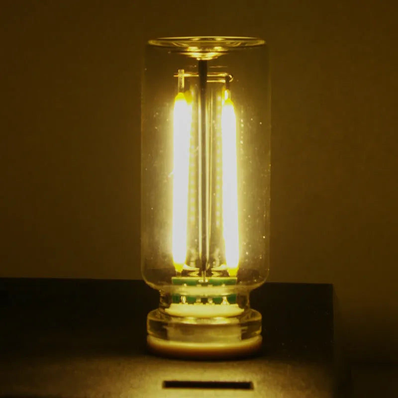 Small transparent glass USB touch night lamp with platinum base on a surface, showing warm white glow.