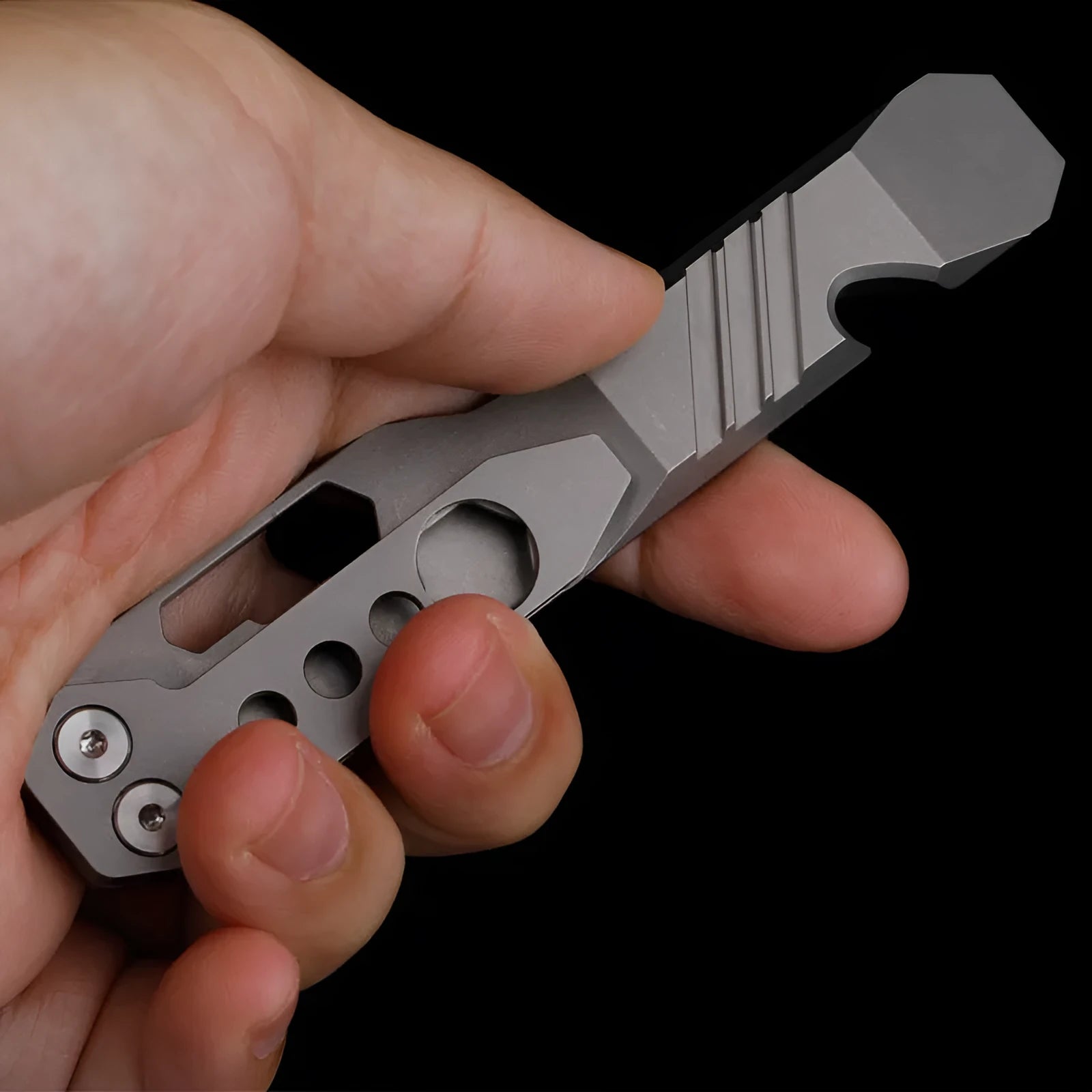 Titanium multi-function crowbar tool with screwdriver tip and bottle opener, shown in stone wash and gun grey finishes.