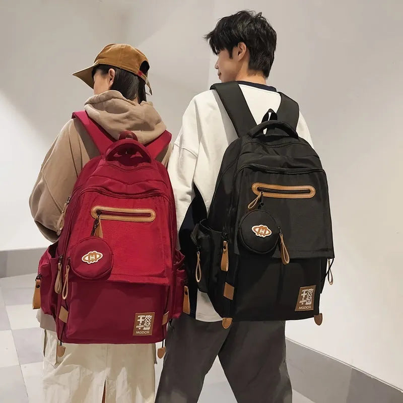 Large nylon school backpack in a solid colour with curved shoulder straps, shown from a side angle.