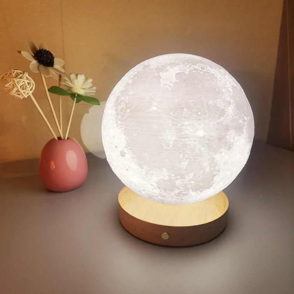 Rotating sleeping moon night lamp on a wooden base, showing three-colour light options.