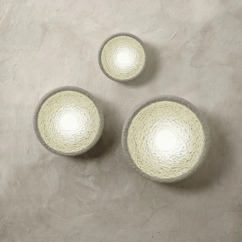 Japanese-style simple white resin wall lamp emitting warm light on a plain wall.