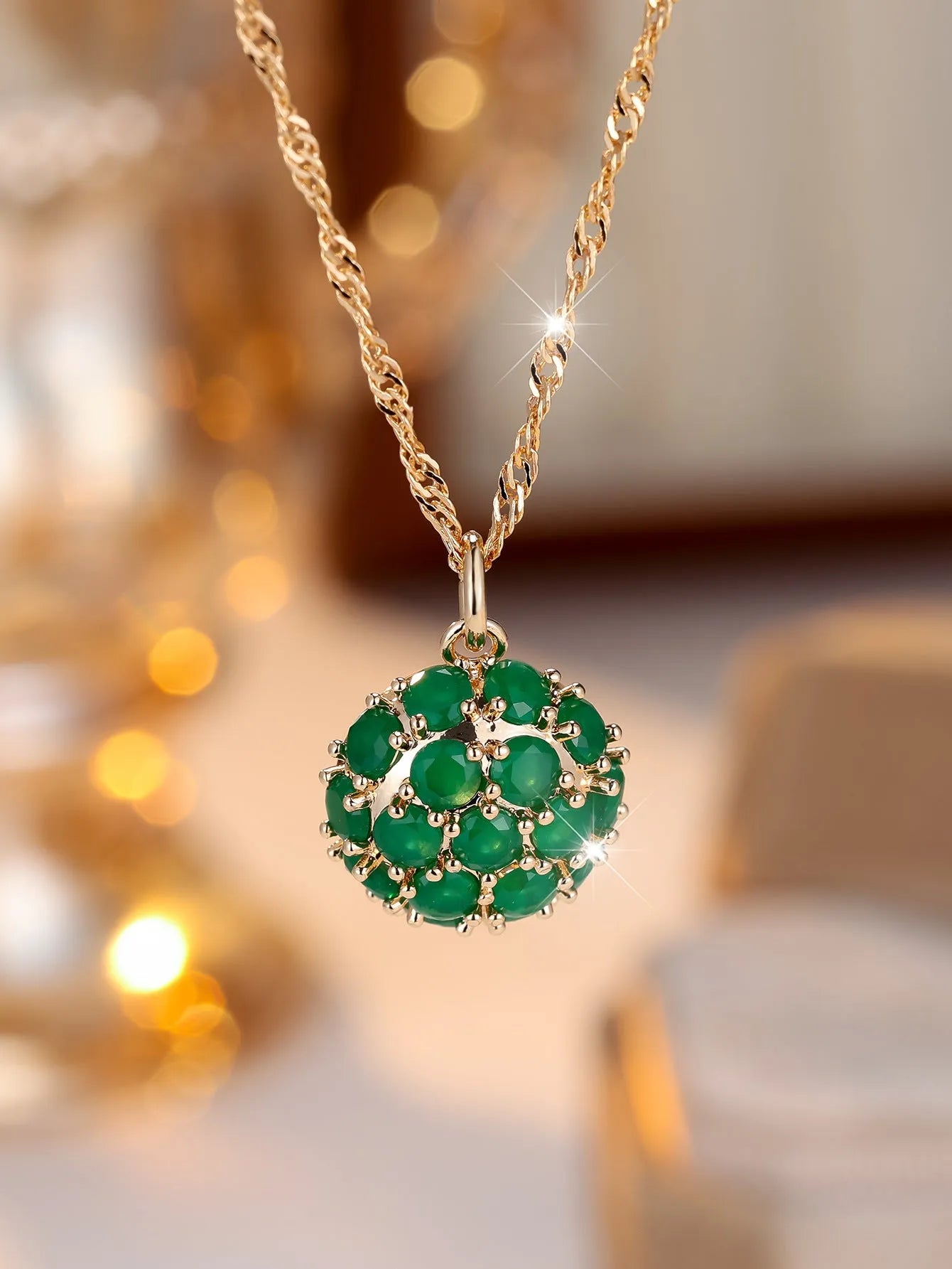 Champagne gold necklace with round emerald pendant and full diamond setting on an adjustable chain.