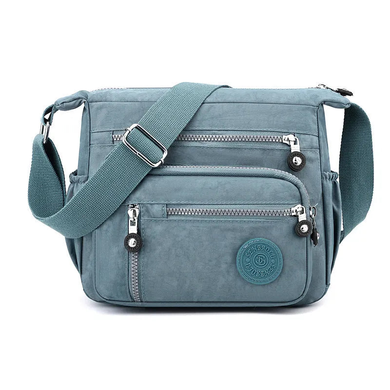 Nylon messenger bag in dark blue with single shoulder strap and soft square design, showing lining cloth interior.