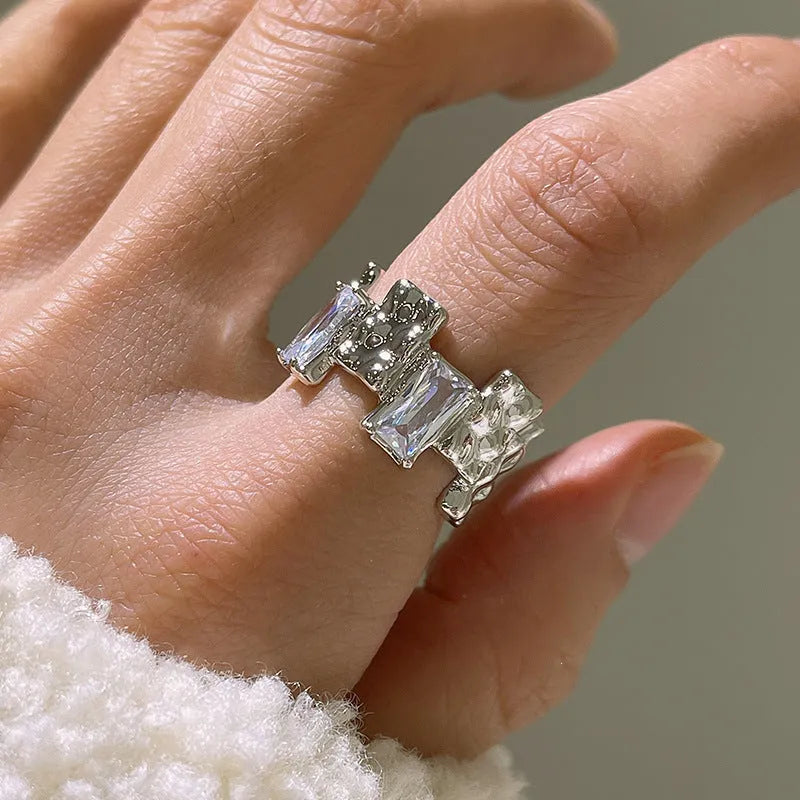 Silver geometric ring with open adjustable band and three-dimensional decoration, shown from multiple angles