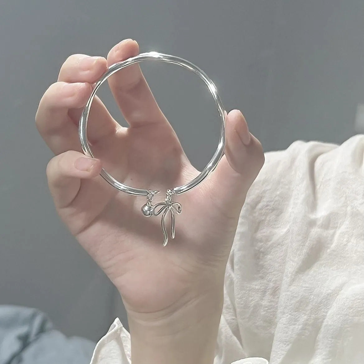 Silver adjustable bow bracelet with zinc alloy construction and electroplated finish on wrist
