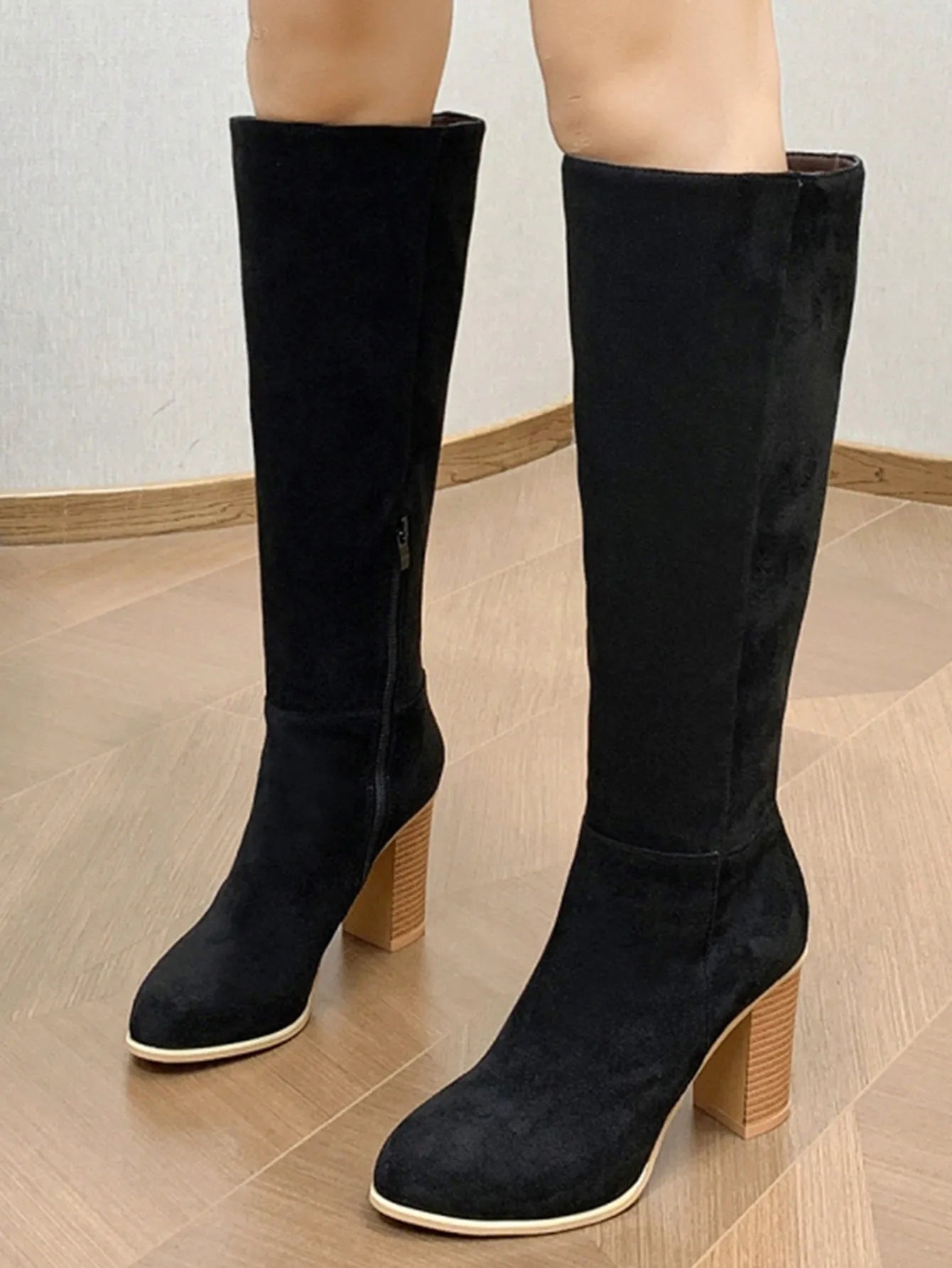 Women's black square toe ankle boots with a block heel on a wooden floor.