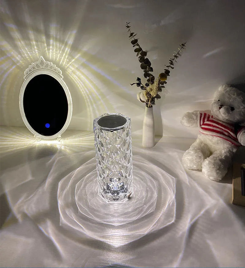 Clear acrylic rose-shaped LED table lamp with touch controls on a wooden surface.