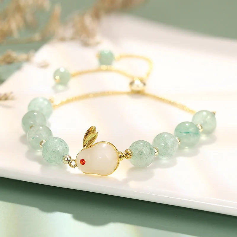 Women's rabbit charm bracelet with green aventurine and strawberry quartz beads, copper and gold details.