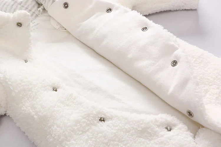 A baby wearing a soft brown cotton lamb-print jumpsuit with long sleeves.