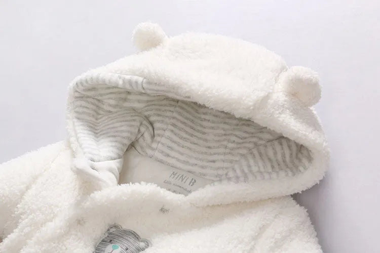 A baby wearing a soft brown cotton lamb-print jumpsuit with long sleeves.