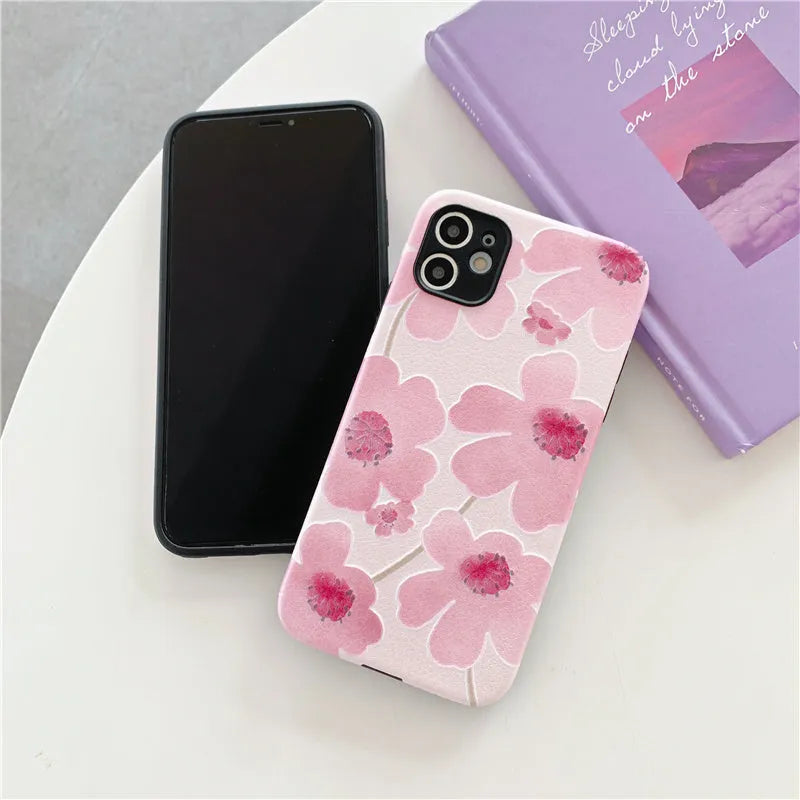 Pink soft rubber flower phone case for iPhone models on a flat surface, showing lanyard hole.