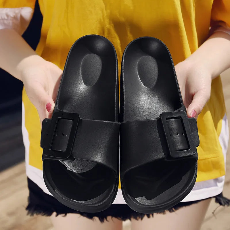 Women's grey blue buckle flip-flop slippers on a light background, showing adjustable strap and cushioned sole.