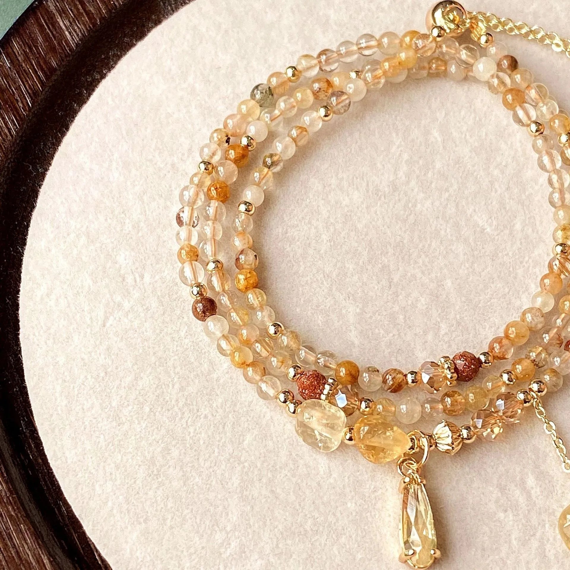 Gold three-circle layered bracelet with caramel citrine stones and a Saturn charm.