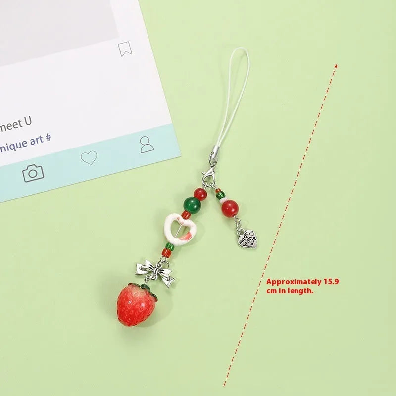 Red and green fruit-themed plastic mobile phone charm and keychain on a white background.
