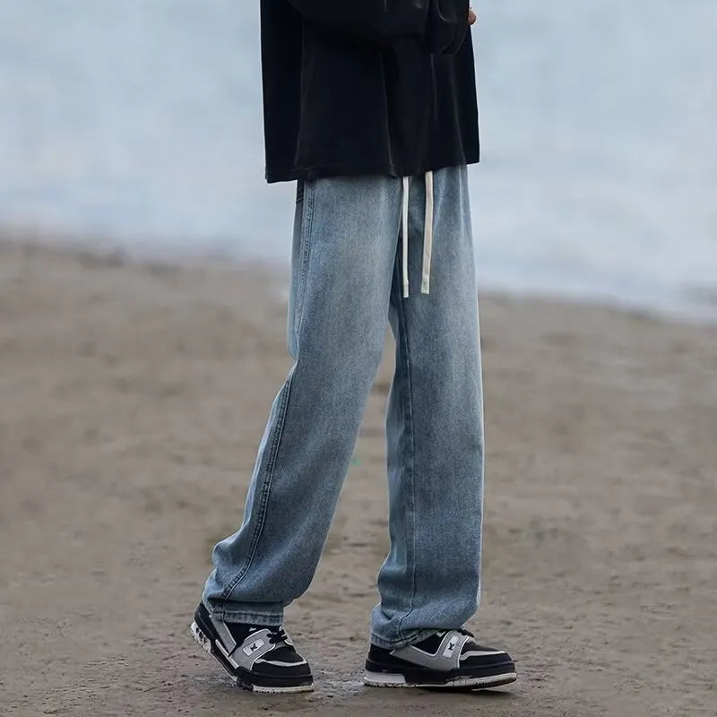 Men's straight-leg blue jeans with drawstring waist closure laid flat