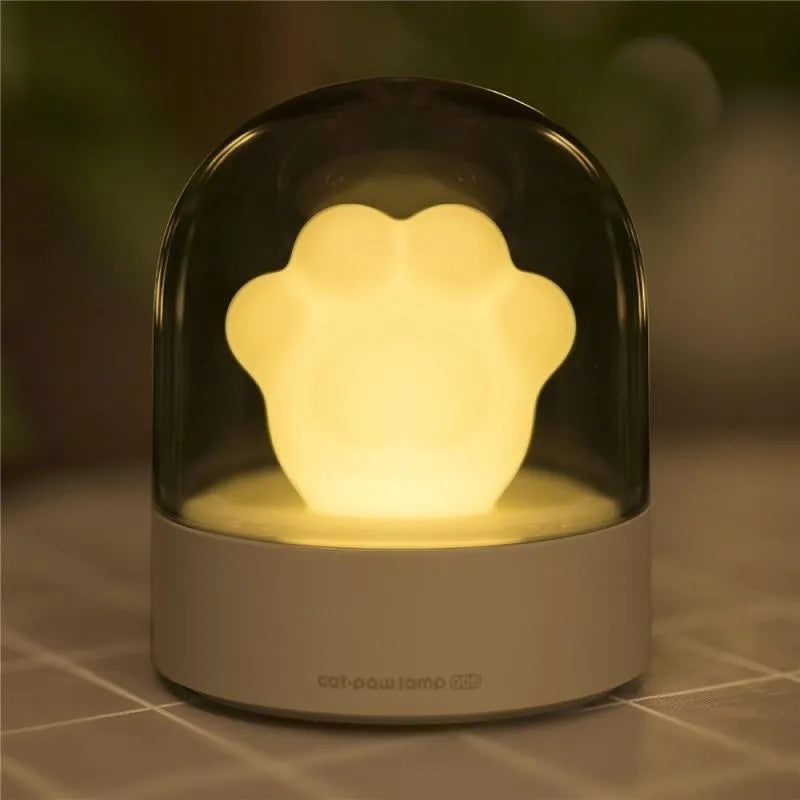 Grey cat paw shaped night light with USB charging port and control button showing soft illumination