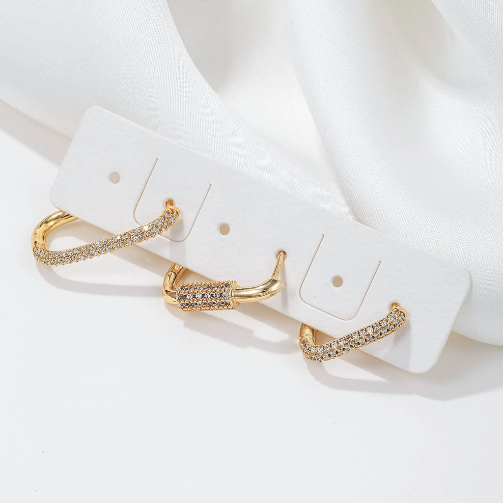 Three geometric copper ear clips with zircon detailing in ellipse and quadrilateral shapes on ear