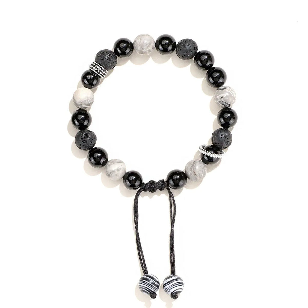 Black agate map stone volcanic rock bracelet with diamond-shaped beads on a wrist.