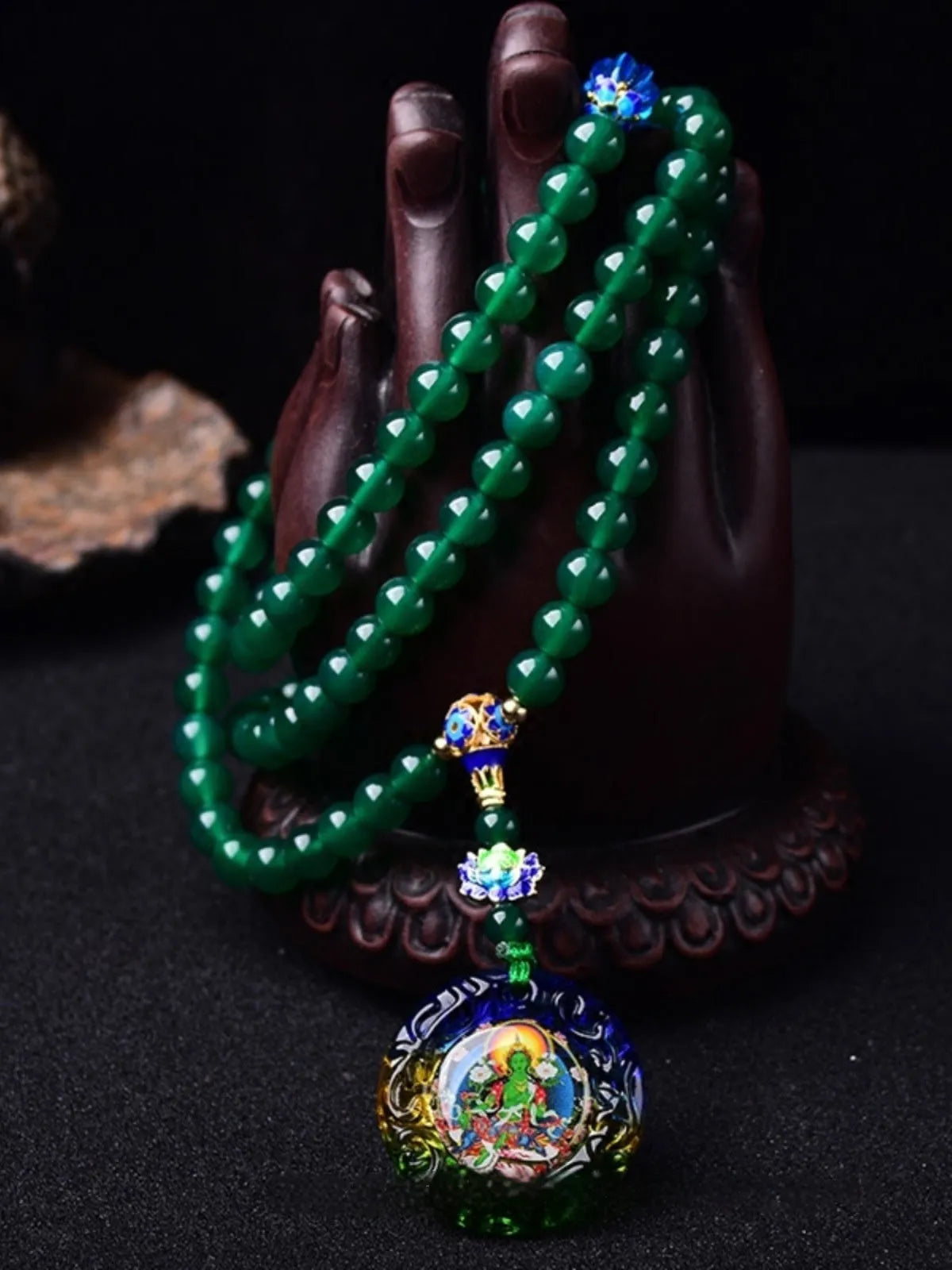 Green agate beaded bracelet with a multi-circle 108-bead thangka pendant on a wrist.