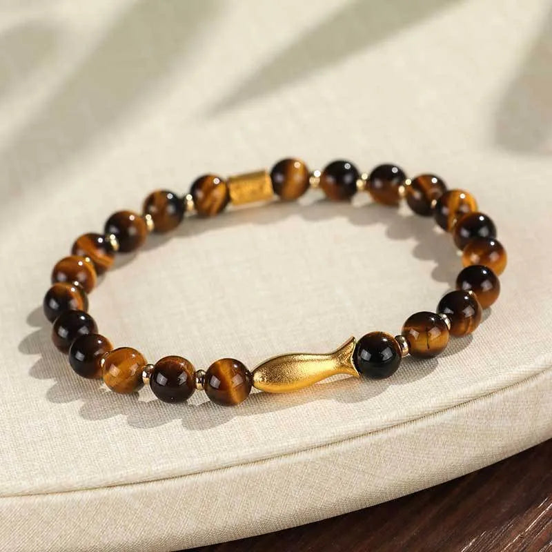 Yellow tiger eye bracelet with small fish bead charm on woman's wrist
