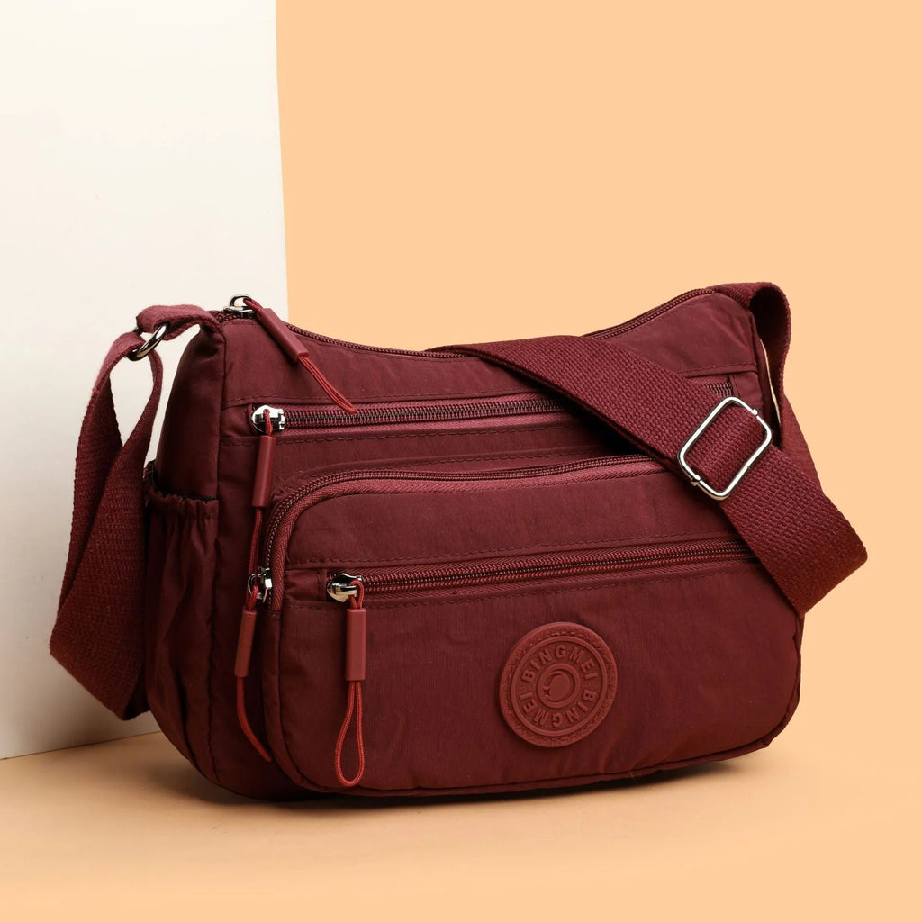 Soft water-repellent nylon crossbody bag in grey with a front 3D pocket.