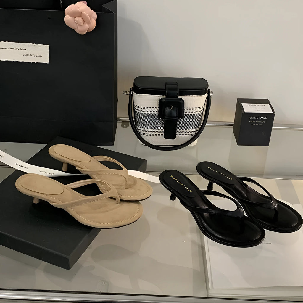 Women's black rubber stiletto flip-flops with round toe and flat head cap on a plain background.