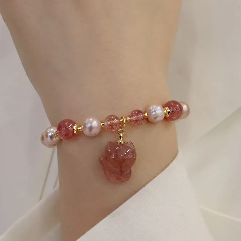 Light pink freshwater pearl bracelet with a strawberry quartz fox charm on a metal chain.