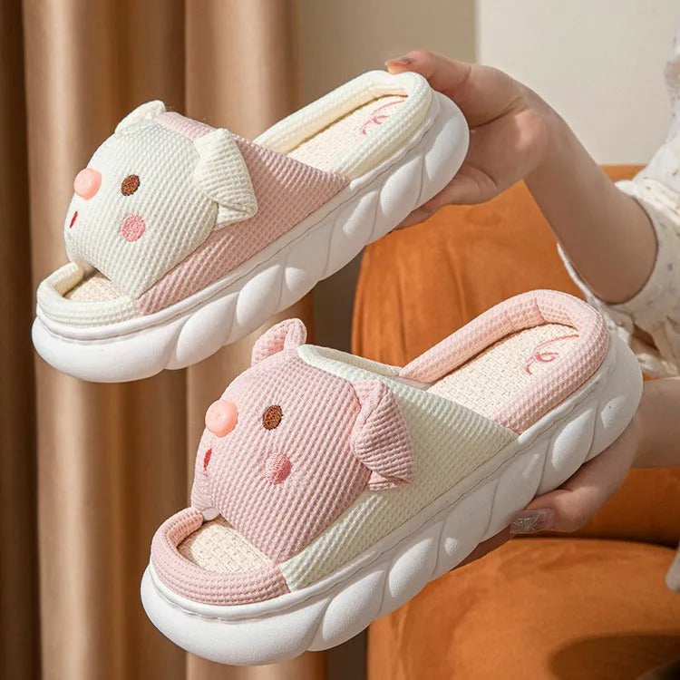 Pair of piggy cute open toe linen flip flop slippers for couples on a plain background.