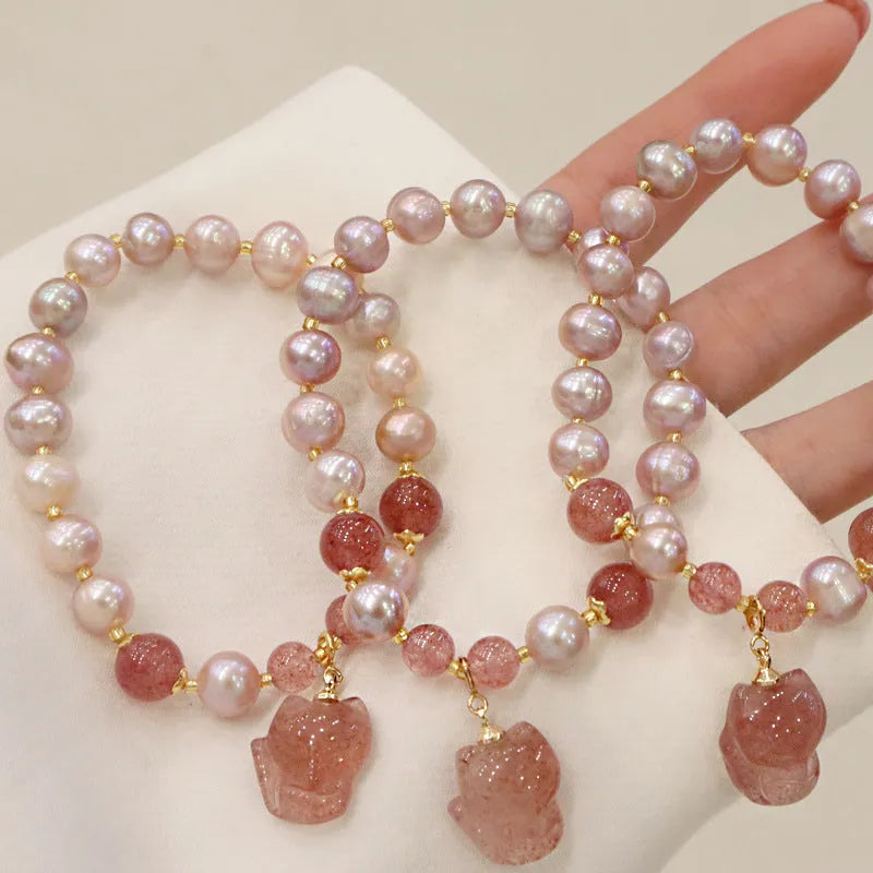 Light pink freshwater pearl bracelet with a strawberry quartz fox charm on a metal chain.