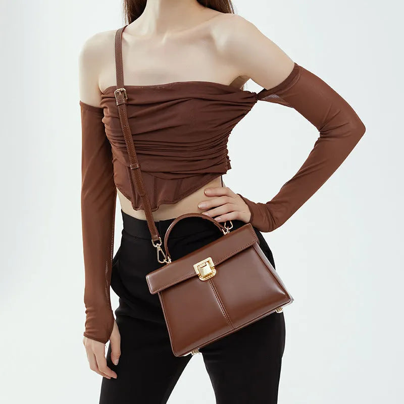 Black leather women's shoulder bag with clasp closure showing internal zippered compartment and adjustable strap
