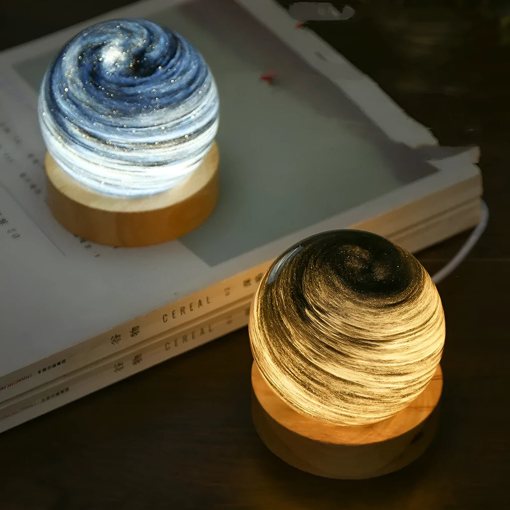 Modern simple style planet night light with USB cable on a wooden surface.