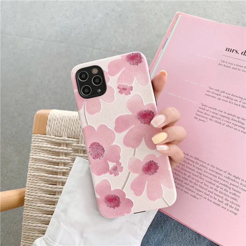 Pink soft rubber flower phone case for iPhone models on a flat surface, showing lanyard hole.