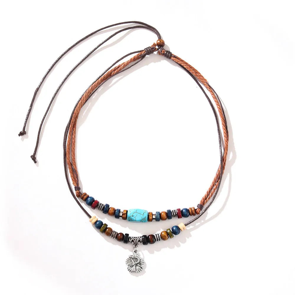 Turquoise wax rope necklace with geometric alloy pendant featuring floral engraving details